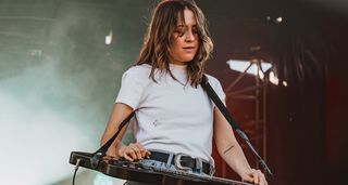 Megal Lovell wears a white T-shirt as she performs outdoors with her lap-steel. For new album Bloom, Megan looked to lap steel luminary David Lindley for inspiration on tones and backline choices.