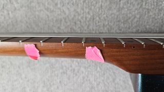 Pink tape on the side of a guitar neck