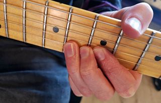 Closeup of three fingers on a fretboard