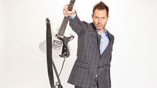 Paul Gilbert wears a suit as he poses with his white FRM200