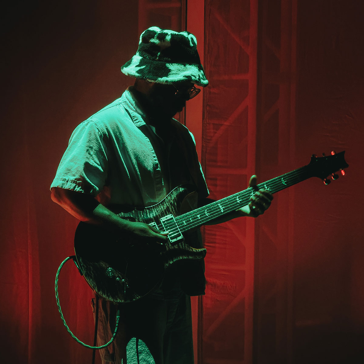 Justus West playing guitar on stage under a green light